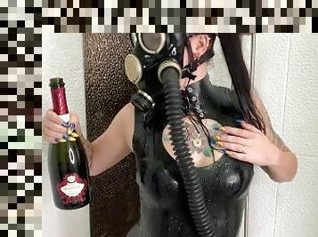 Dominatrix Nika in a gas mask pours wine over her latex body. Latex fetish