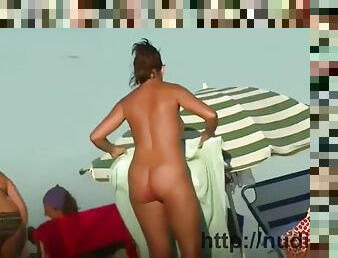 Nudist video at the beach has shy girl playing in the water