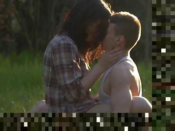 Young couple in the grass makes erotic love