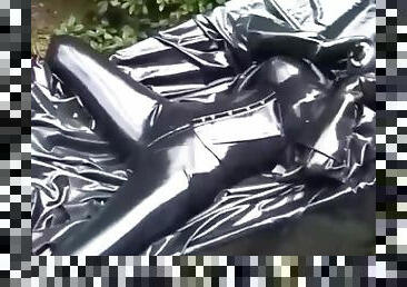 Latex girl full in black rubber and Gasmask chill outs outdoor in garden in a heavy rubber hammock