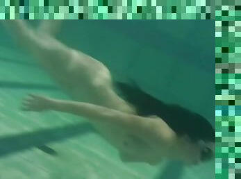 Beautiful naked girl swims in the pool