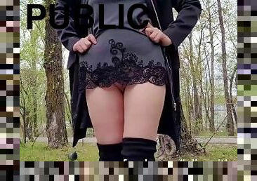 Hot girl in a very short dress walks in the park and flashes her puss