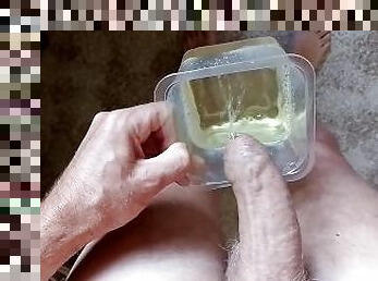 Close up sexy guy pissing in a plastic container