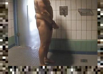 Guy plays with his big cock and tight butt hole in a public shower room