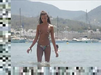 Tanned beach babe is topless for the day